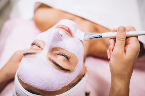 Cosmetologist applying mask on a face of client in a beauty salon